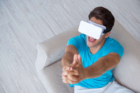 Young man wearing VR glasses relaxing on couch sofa