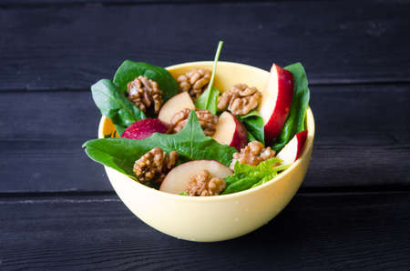 Spinach salad with nuts and apples served on tableの写真素材