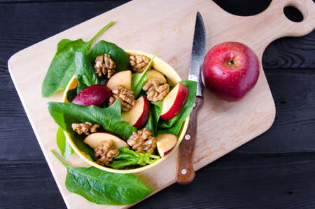 Spinach salad with nuts and apples served on tableの写真素材