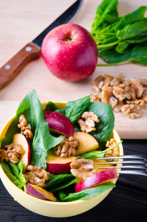 Spinach salad with nuts and apples served on tableの写真素材