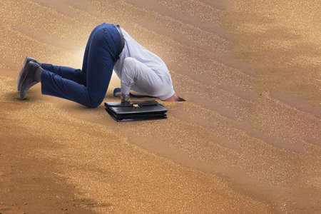 Businessman hiding his head in sand escaping from problemsの写真素材