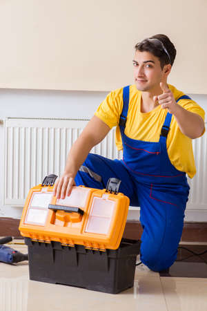 Young repairman contractor repairing heating panelの写真素材