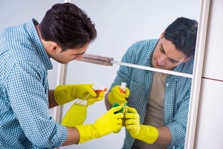 Young man cleaning mirror at hotel roomの写真素材