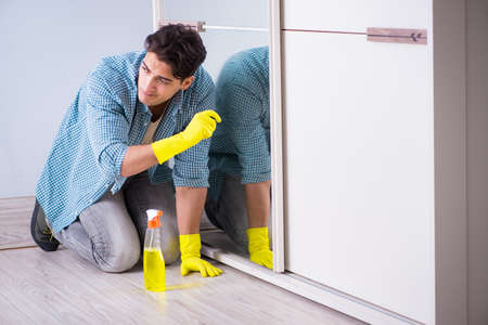 Young man cleaning mirror at hotel room
