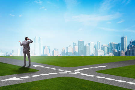 Young businessman at crossroads in uncertainty conceptの写真素材