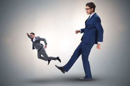 Bad angry boss kicking employee in business conceptの写真素材