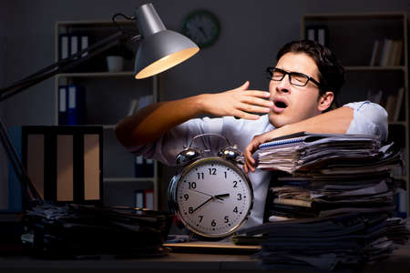Young businessman working overtime late in officeの写真素材