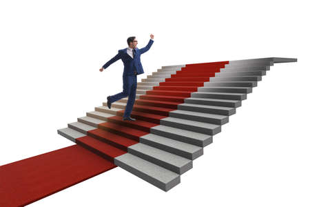 Young businessman climbing stairs and red carpet on white backgroundの写真素材
