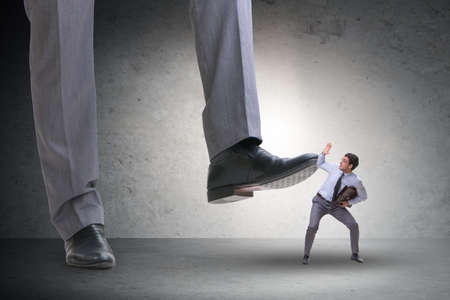 Bad angry boss stamping on employee in business conceptの写真素材