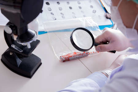 Criminologist police chemist looking at crime evidence
