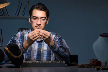 Young male jeweller working at night in his workshopの写真素材