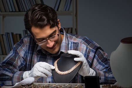 Young male jeweller working at night in his workshopの写真素材