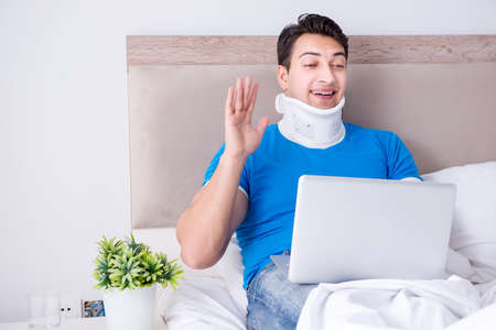Young man with neck injury in the bedの写真素材