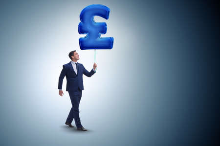 Businessman walking with inflatable british pound signの写真素材