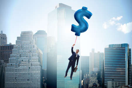 Businessman flying on dollar sign inflatable balloonの写真素材