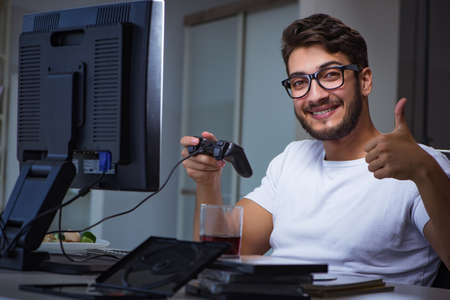 Young man playing games long hours late in the office