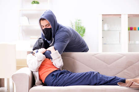 Armed man assaulting young woman at homeの写真素材