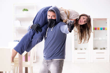 Armed man assaulting young woman at homeの写真素材