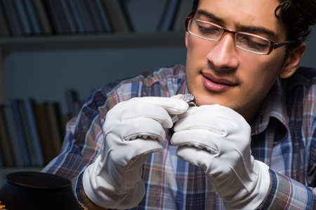 Young male jeweller working at night in his workshopの写真素材