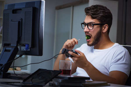 Young man playing games long hours late in the office