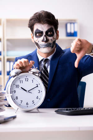 Businessmsn with scary face mask working in officeの写真素材