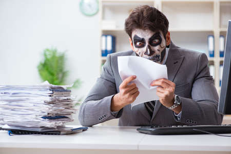 Businessmsn with scary face mask working in officeの写真素材