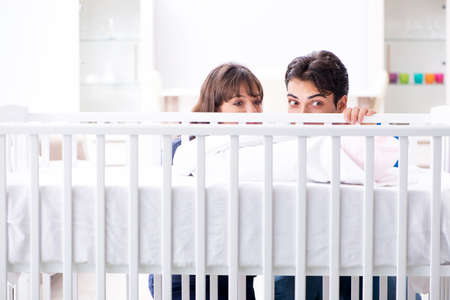 Happy young family at baby bed cotの写真素材