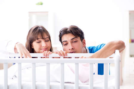 Happy young family at baby bed cotの写真素材