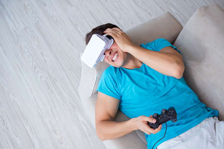 Young man wearing VR glasses relaxing on couch sofa