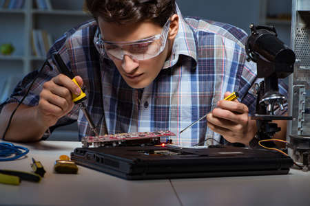 Young repair technician soldering electrical parts on motherboarの写真素材