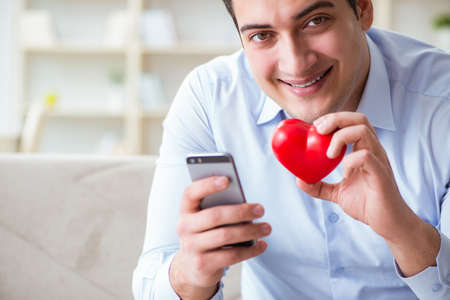 Young man chatting with his sweetheart over mobile phoneの写真素材