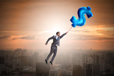 Businessman flying on dollar sign inflatable balloonの写真素材