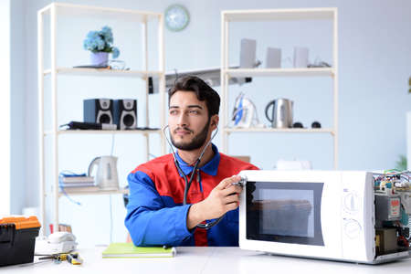 Young repairman fixing and repairing microwave ovenの写真素材