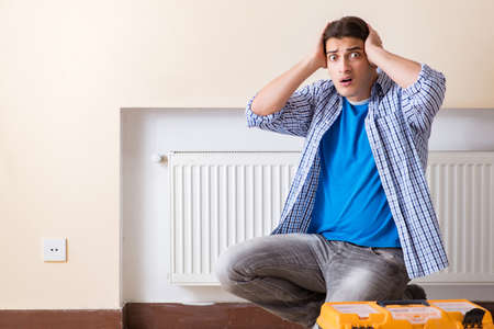 Young repairman contractor repairing heating panelの写真素材