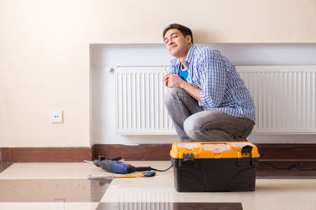 Young repairman contractor repairing heating panelの写真素材