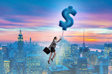 Businesswoman flying on dollar sign inflatable balloonの写真素材