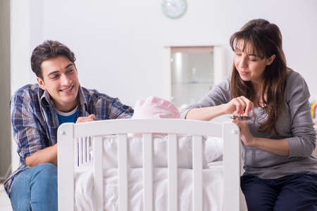 Young parents with their newborn baby near bed cotの写真素材