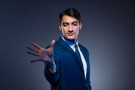 Businessman pressing virtual buttons on gray backgroundの写真素材