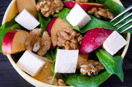 Spinach salad with nuts and apples served on tableの写真素材