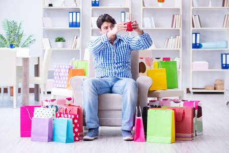 Young man after excessive shopping at homeの写真素材