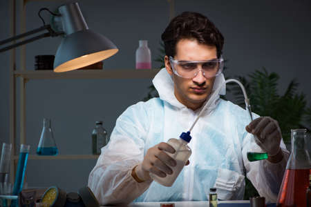 Young male lab chemist late at night in overtime time