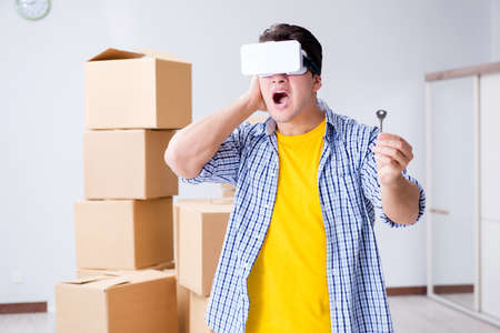 Young man wearing VR glasses moving in new apartment