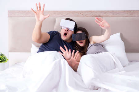 Wife and husband with virtual reality goggles in the bedの写真素材
