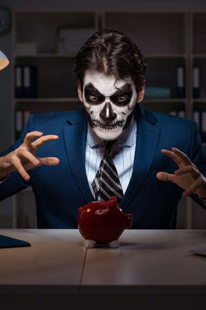 Businessman with scary face mask working late in officeの写真素材