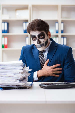 Businessmsn with scary face mask working in officeの写真素材