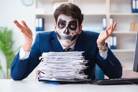 Businessmsn with scary face mask working in officeの写真素材