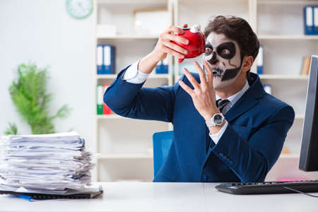 Businessmsn with scary face mask working in officeの写真素材