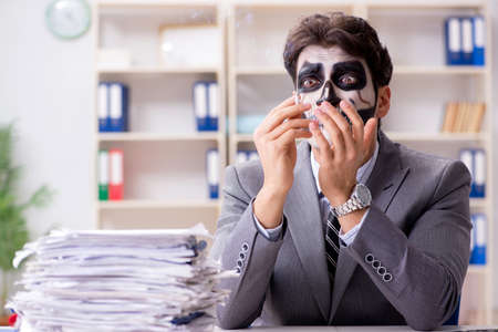 Businessmsn with scary face mask working in officeの写真素材