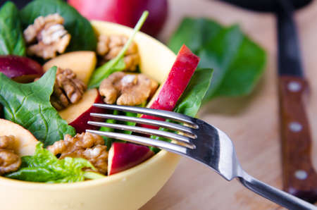 Spinach salad with nuts and apples served on tableの写真素材