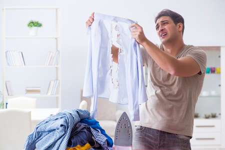 Inattentive husband burning clothing while ironingの写真素材